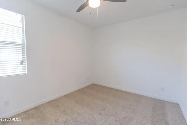 an empty room with a window and a fan