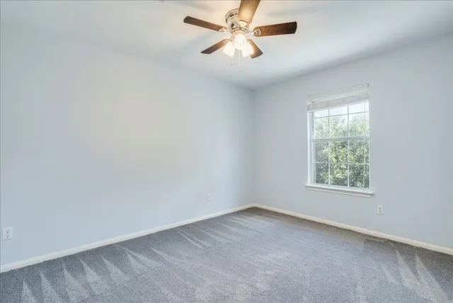 an empty room with a window and a fan