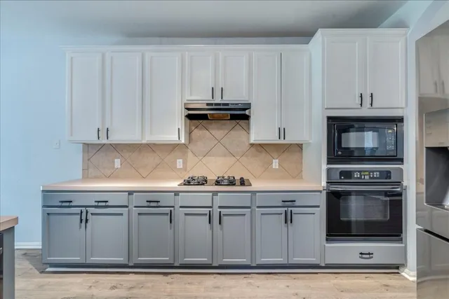 a kitchen with stainless steel appliances granite countertop a stove and white cabinets