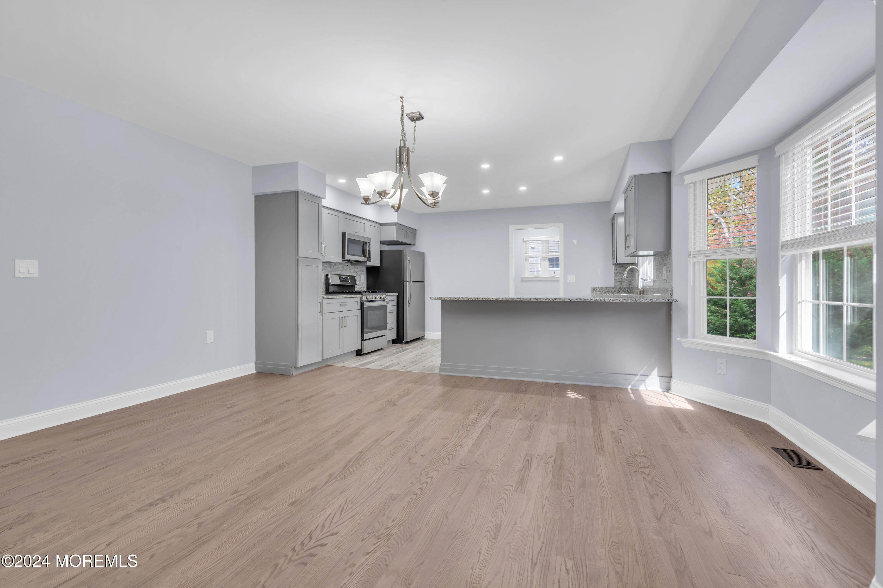 239 Sunset Drive Forked River, NJ 08731 - Photo 17 of 35 an empty room with wooden floor and kitchen view
