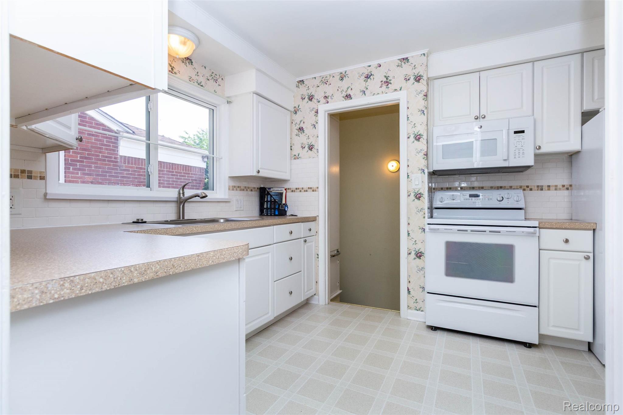 14869 Champaign Road Allen Park, MI 48101 - Photo 11 of 34 Bright kitchen featuring white cabinetry, light-colored countertops, a tile backsplash, and durable patterned flooring