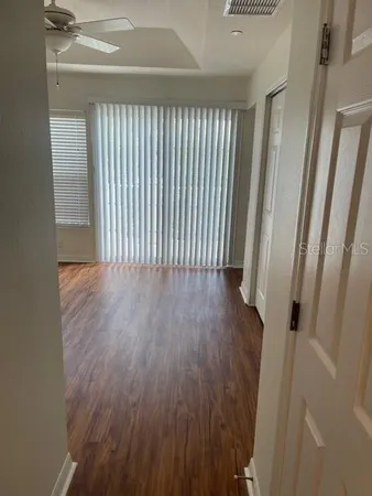 a view of a hallway with wooden floor and a bathroom