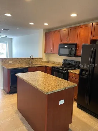 a kitchen with stainless steel appliances granite countertop a sink a stove a refrigerator a microwave oven with granite countertops and cabinets