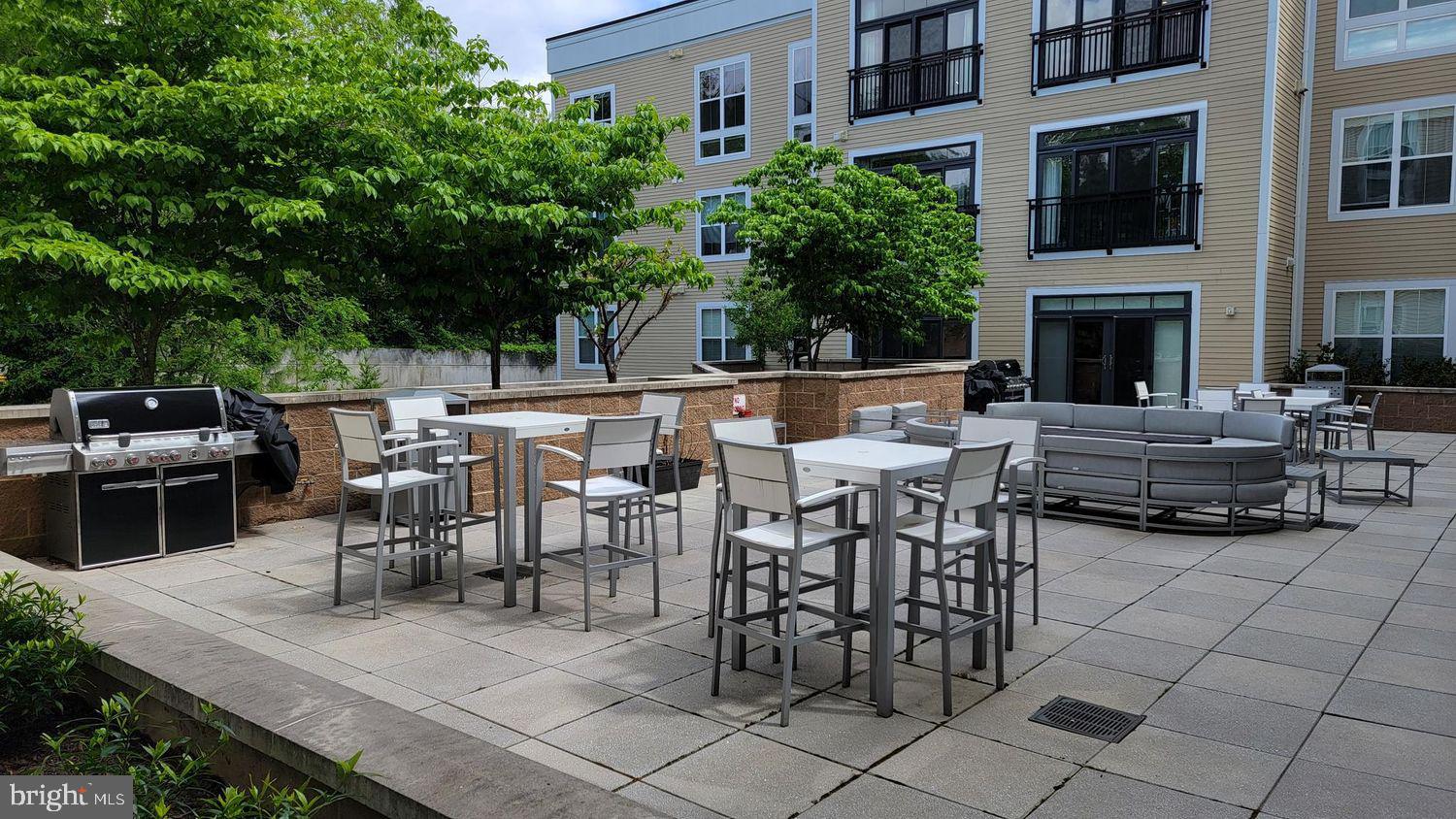 989 South Buchanan Street, Unit 312 Arlington, VA 22204 - Photo 35 of 45 a view of a patio with dining table and chairs with a fire pit and a barbeque grill
