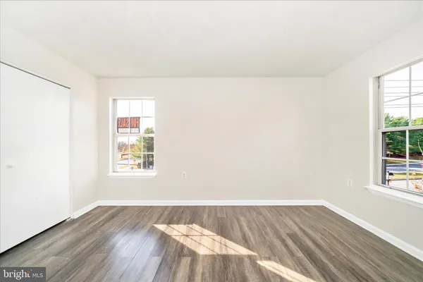 an empty room with wooden floor and windows