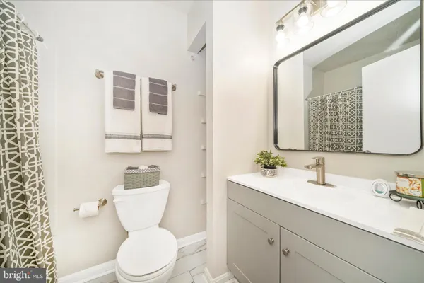 a bathroom with a toilet a sink a mirror a window and vanity