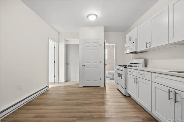 a kitchen with granite countertop white cabinets and white appliances