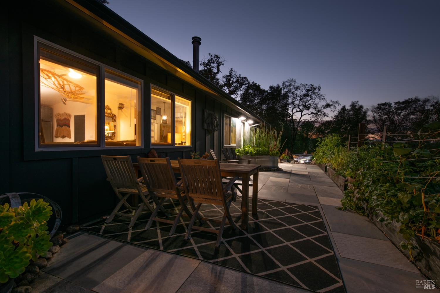 22855 Chianti Road Geyserville, CA 95411 - Photo 27 of 76 a view of a porch with dining table and chairs with potted plants and big yard