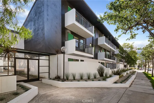 a view of a white house with large windows and a tree