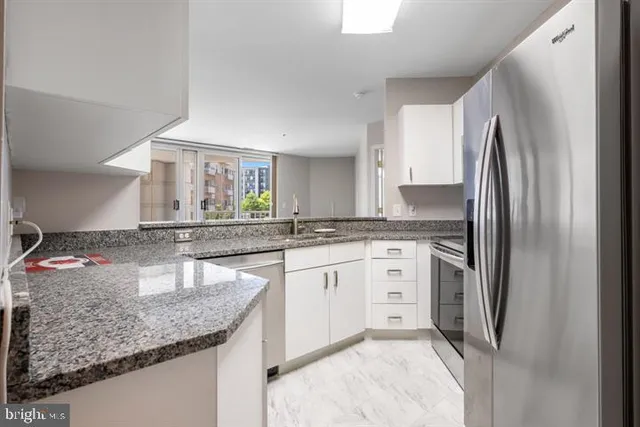 a kitchen with stainless steel appliances granite countertop a sink refrigerator and cabinets