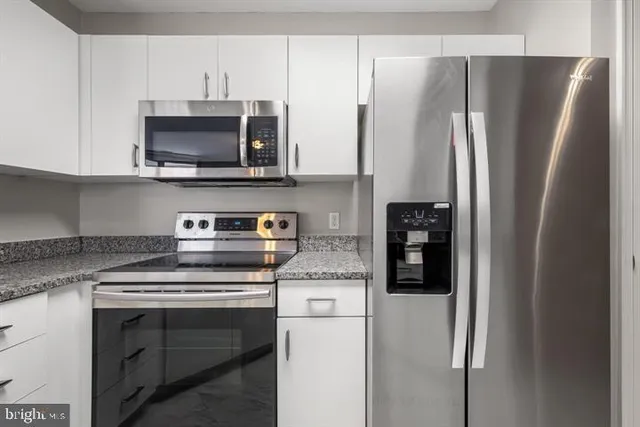 a kitchen with stainless steel appliances white cabinets and a refrigerator