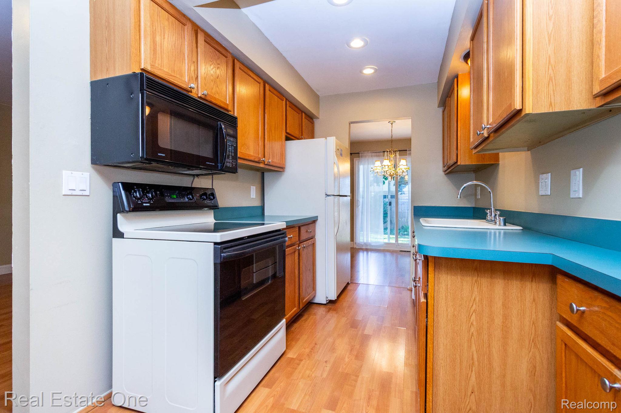 111 Manor Way Rochester, MI 48309 - Photo 12 of 36 Galley kitchen featuring wood-finish flooring, wood cabinetry, and blue countertops