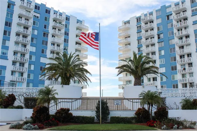 a front view of multi story residential apartment building with yard and sign board