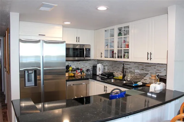 a kitchen with stainless steel appliances granite countertop a sink refrigerator and cabinets