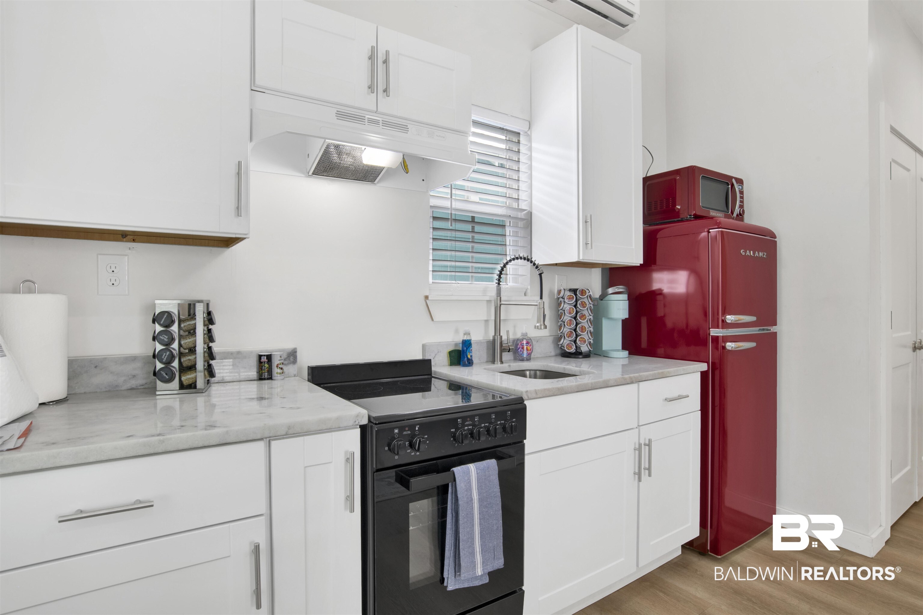 555 Congress Street Mobile, AL 36603 - Photo 9 of 27 Kitchen featuring black electric range oven, white cabinetry, light stone counters, light wood-style floors, and freestanding refrigerator