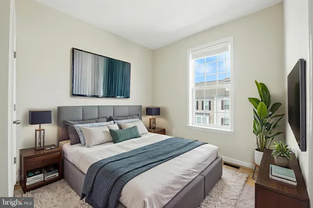 a bedroom with a bed table and flat screen tv