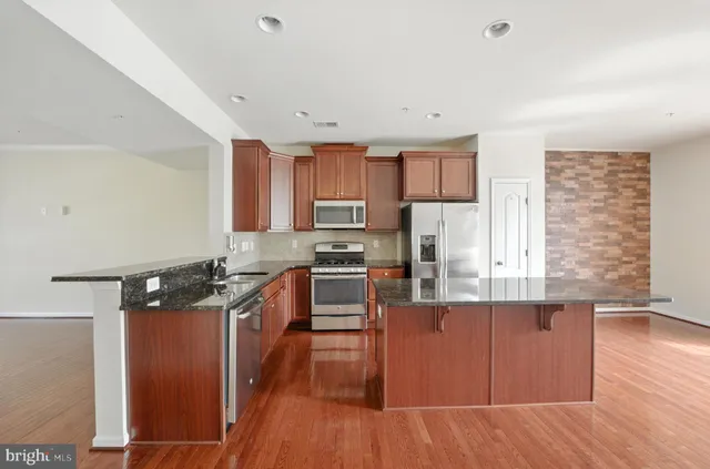a kitchen with granite countertop wooden floors and wooden cabinets