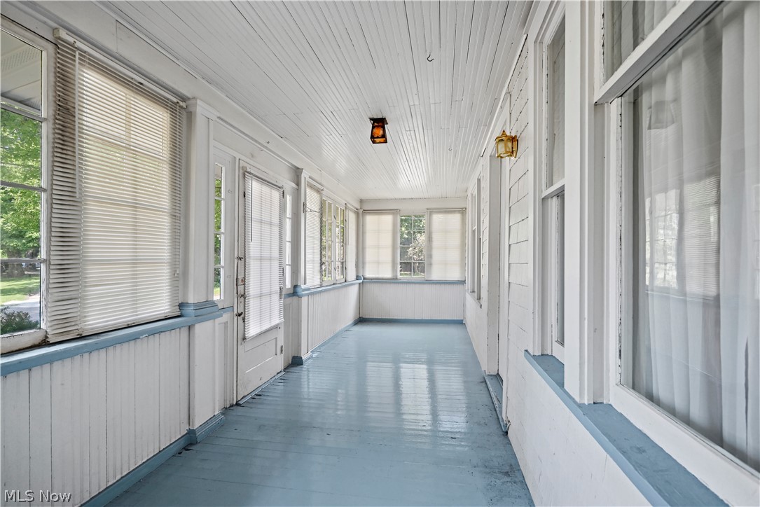 503 Ravenna Road Newton Falls, OH 44444 - Photo 24 of 34 Enclosed porch featuring a wood-finish ceiling, multiple windows, a light blue painted floor, and two wall-mounted light fixtures