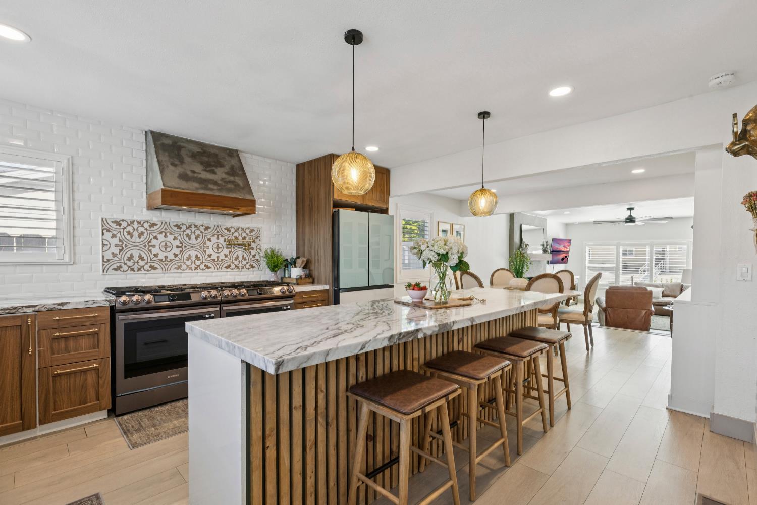 a kitchen with stainless steel appliances granite countertop a stove a sink a oven a dining table and chairs with wooden floor