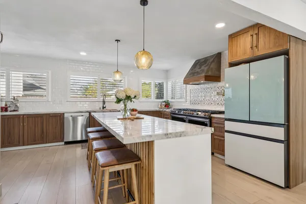 a kitchen with stainless steel appliances granite countertop a sink a stove and a wooden floors