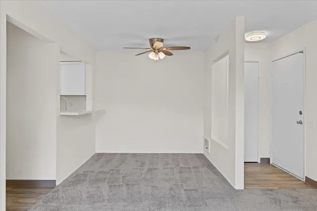 an empty room with a chandelier fan and windows