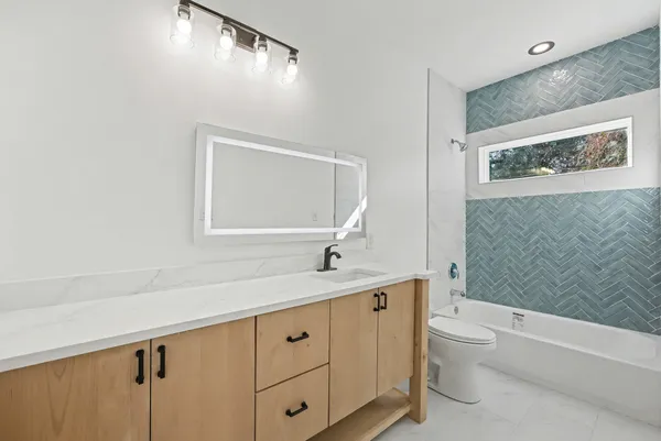 a bathroom with a granite countertop sink a toilet and a bathtub