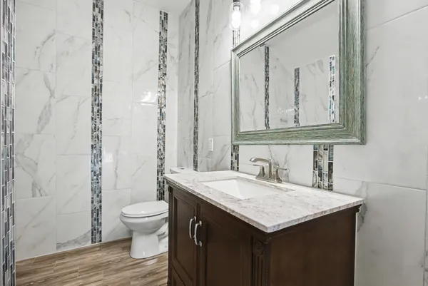 a bathroom with a granite countertop sink and a toilet