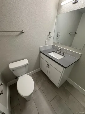 a bathroom with a granite countertop toilet and a sink