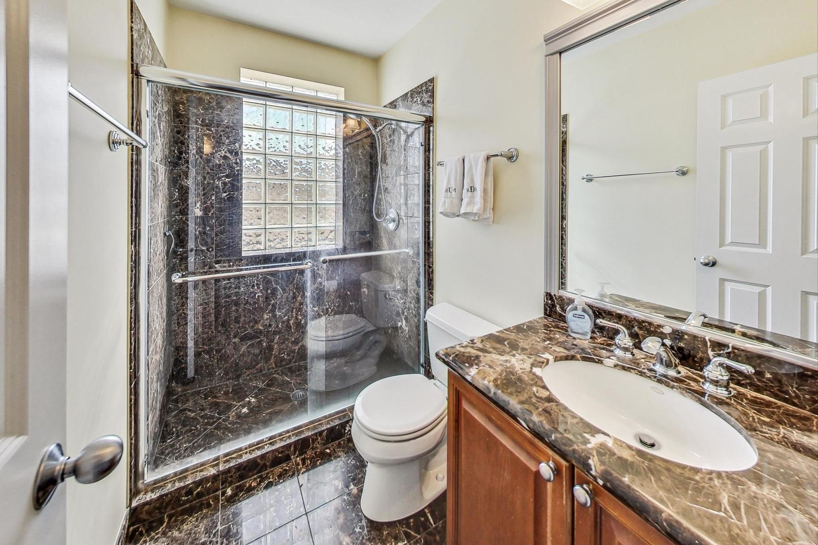 951 West Fletcher Street, Unit 2 Chicago, IL 60657 - Photo 21 of 26 a bathroom with a granite countertop sink toilet a mirror and shower
