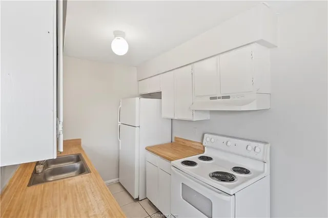 a kitchen with a sink a refrigerator and wooden floor