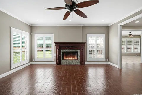 a view of an empty room with wooden floor fireplace and a window