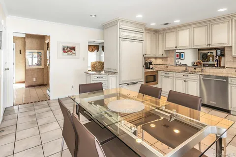 a open kitchen with stainless steel appliances granite countertop a stove a sink a refrigerator a dining table and chairs