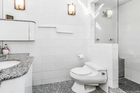 a bathroom with a granite countertop toilet sink and mirror
