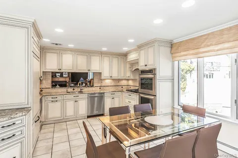 a kitchen with stainless steel appliances granite countertop a stove top oven a sink dishwasher and a refrigerator with wooden floor