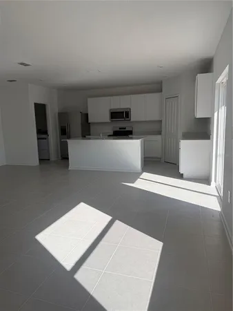 a living room with stainless steel appliances kitchen island a tub sink and cabinets