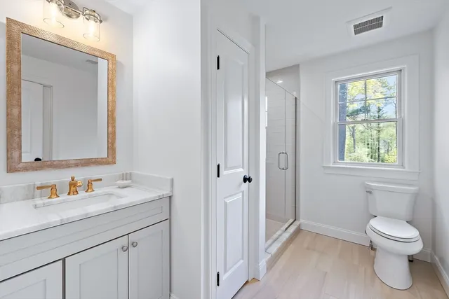 a bathroom with a toilet a sink a mirror and a window