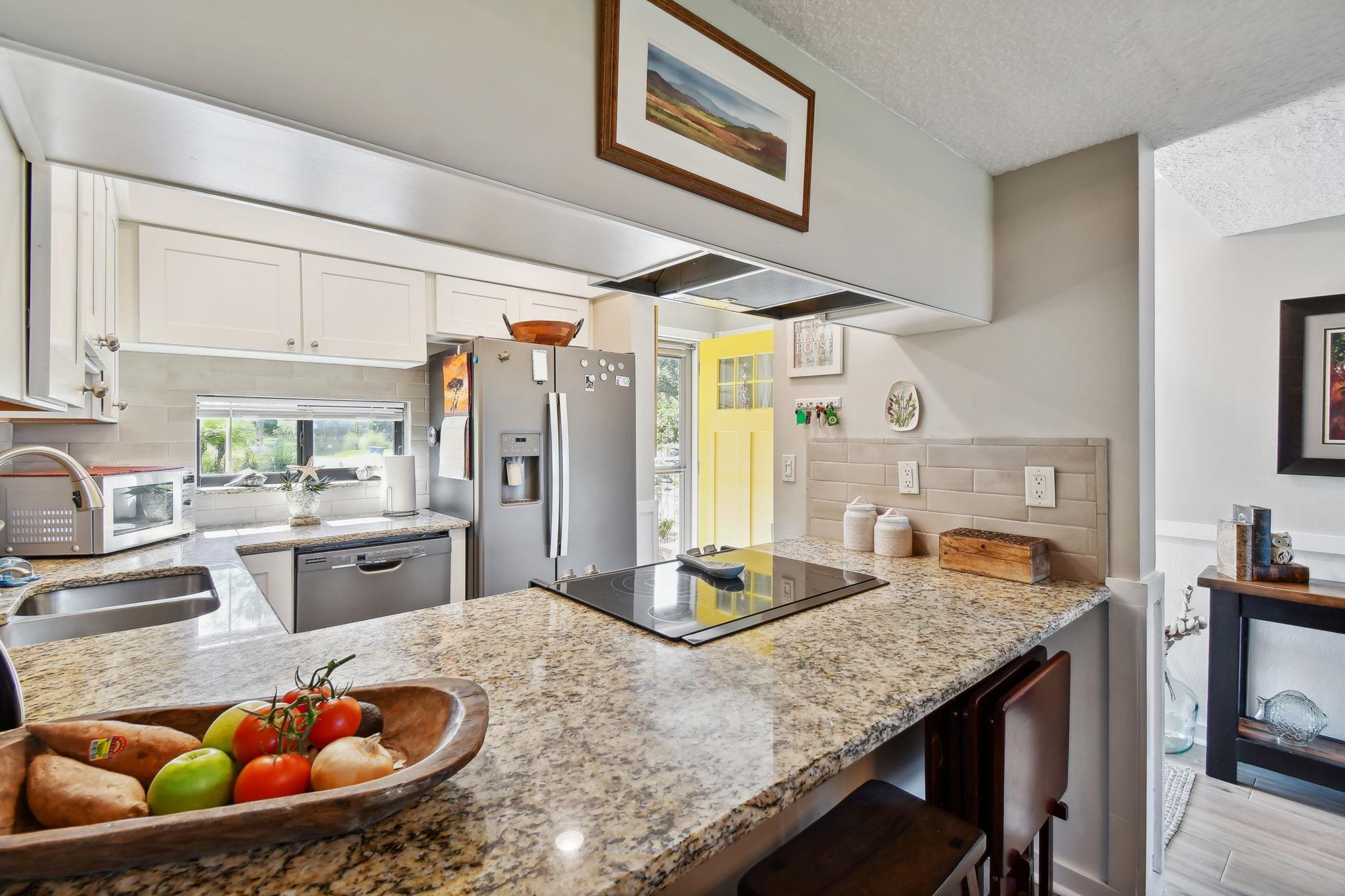 131 Rio Del Mar Street, Unit E St. Augustine, FL 32080 - Photo 17 of 67 a kitchen with stainless steel appliances granite countertop a sink dishwasher and cabinets with wooden floor