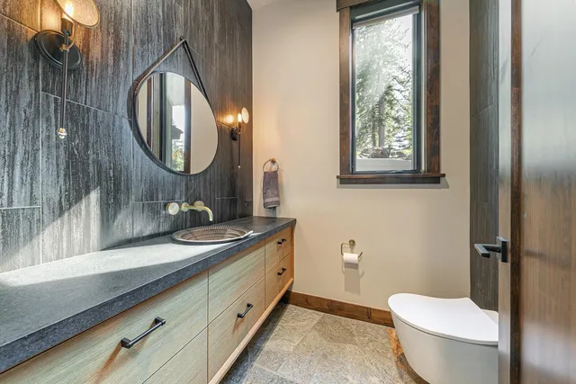 a bathroom with a granite countertop toilet a sink and a mirror