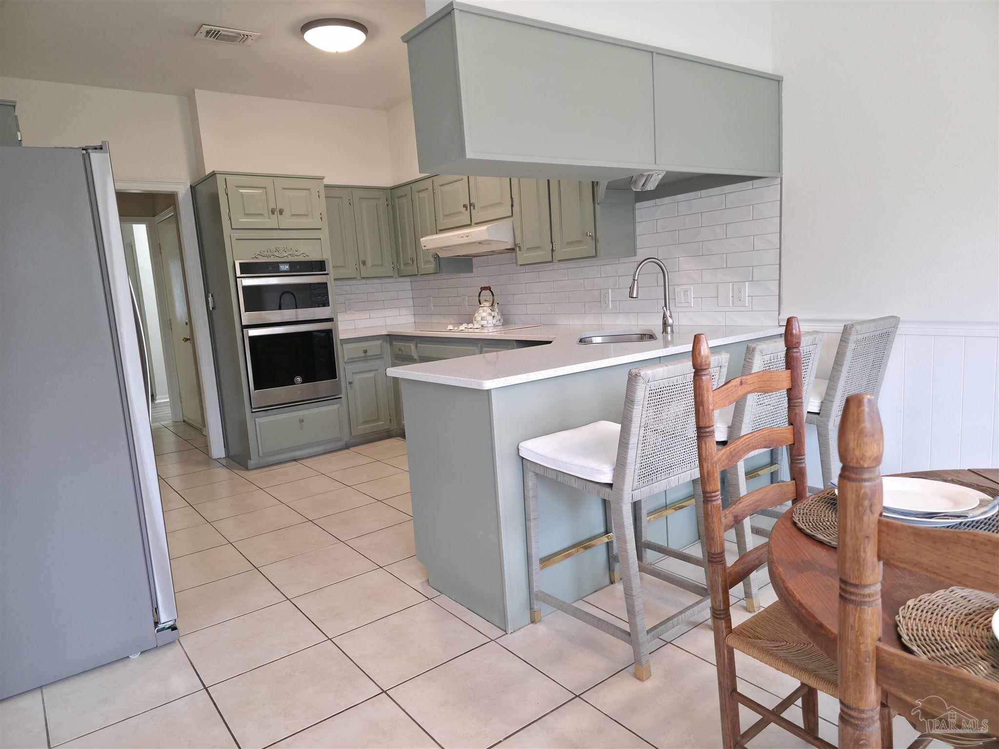 3249 Windmill Circle Cantonment, FL 32533 - Photo 9 of 44 a kitchen with stainless steel appliances a sink counter space and chairs