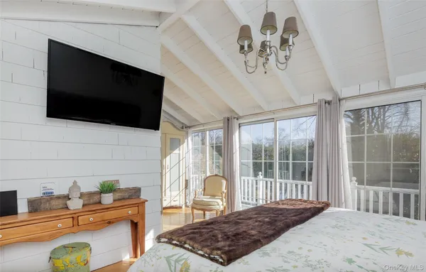 a bedroom with a bed a flat screen tv and a window