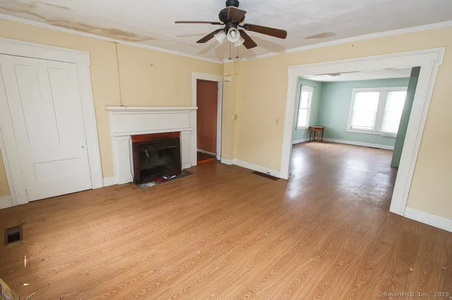 a view of empty room with wooden floor and fan