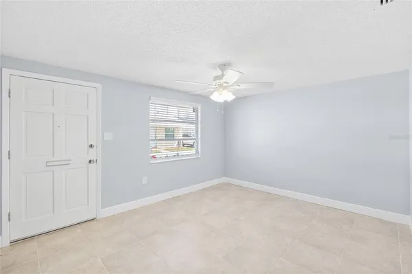 an empty room with windows and chandelier fan