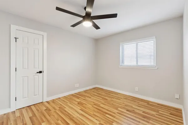 a view of empty room with wooden floor and fan