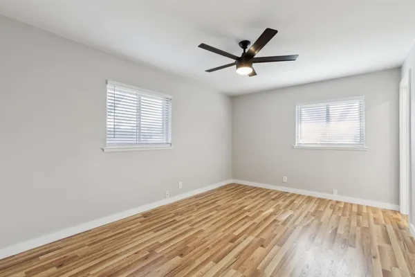 a view of a big room with wooden floor and windows