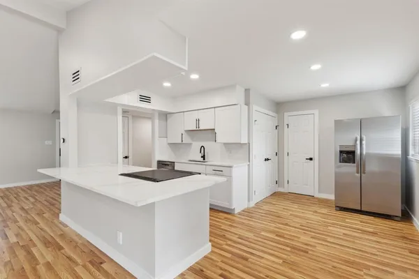 a kitchen that has a lot of white cabinets and stainless steel appliances