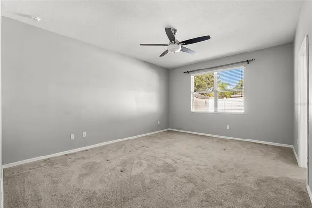 an empty room with a window and a fan