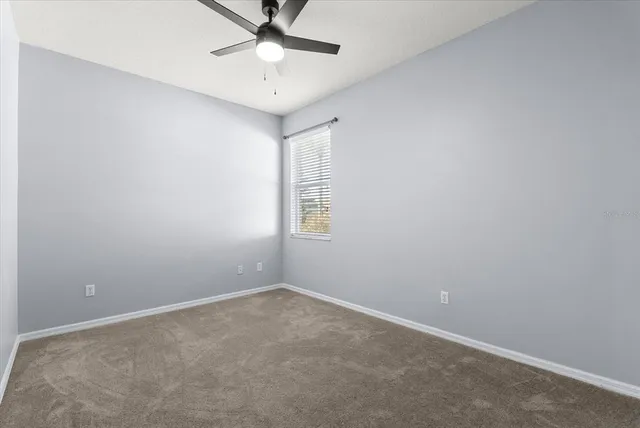 an empty room with a window and a fan