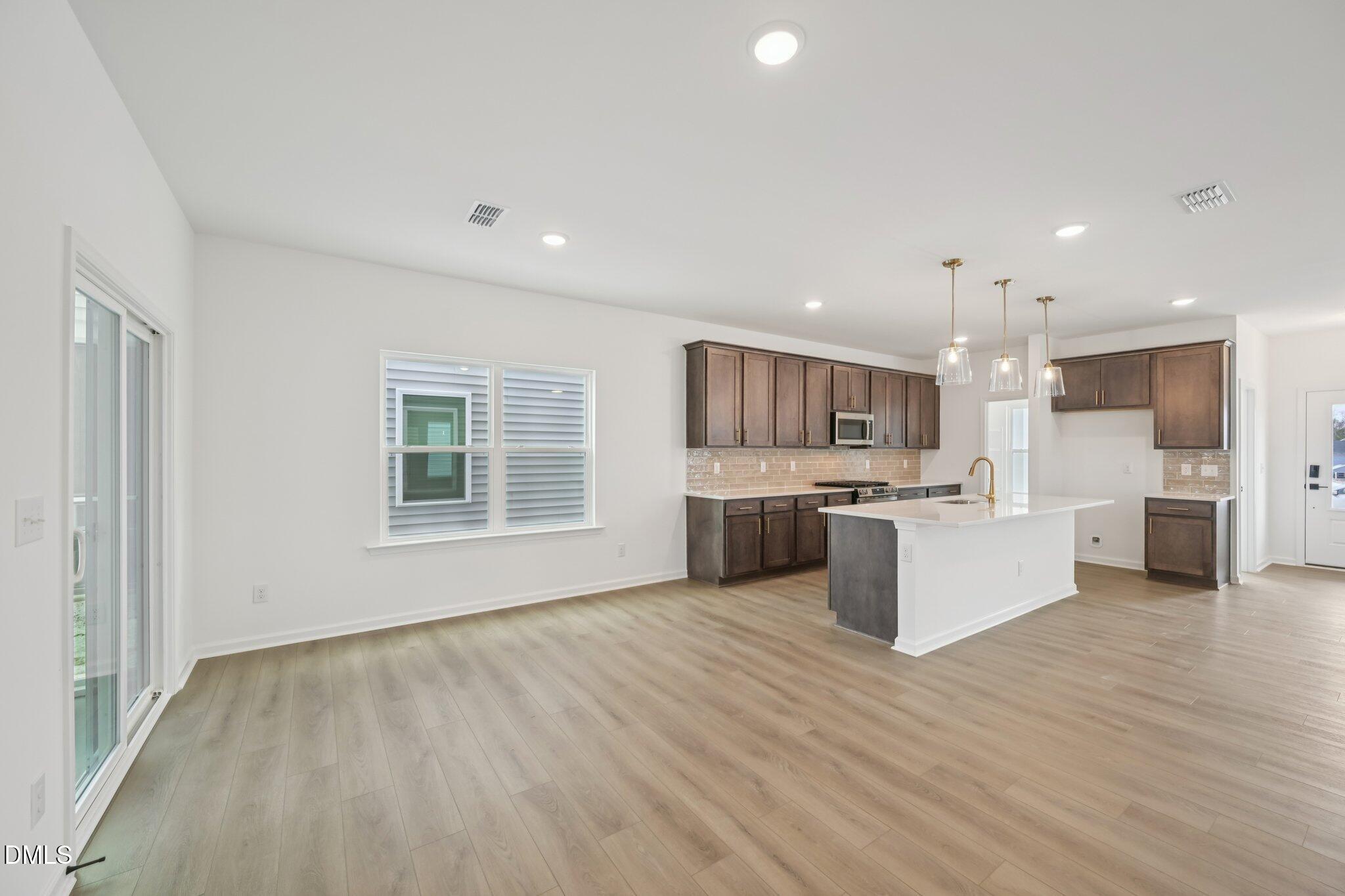 309 Marvel Drive, Unit 147 Rolesville, NC 27571 - Photo 13 of 39 a large white kitchen with kitchen island a sink wooden floor and stainless steel appliances