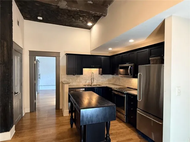 a kitchen with stainless steel appliances kitchen island granite countertop a table chairs and a refrigerator