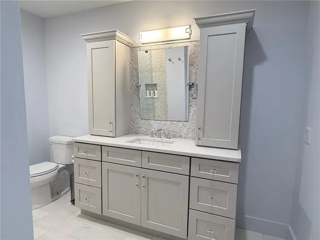 a bathroom with a granite countertop sink a toilet and a mirror